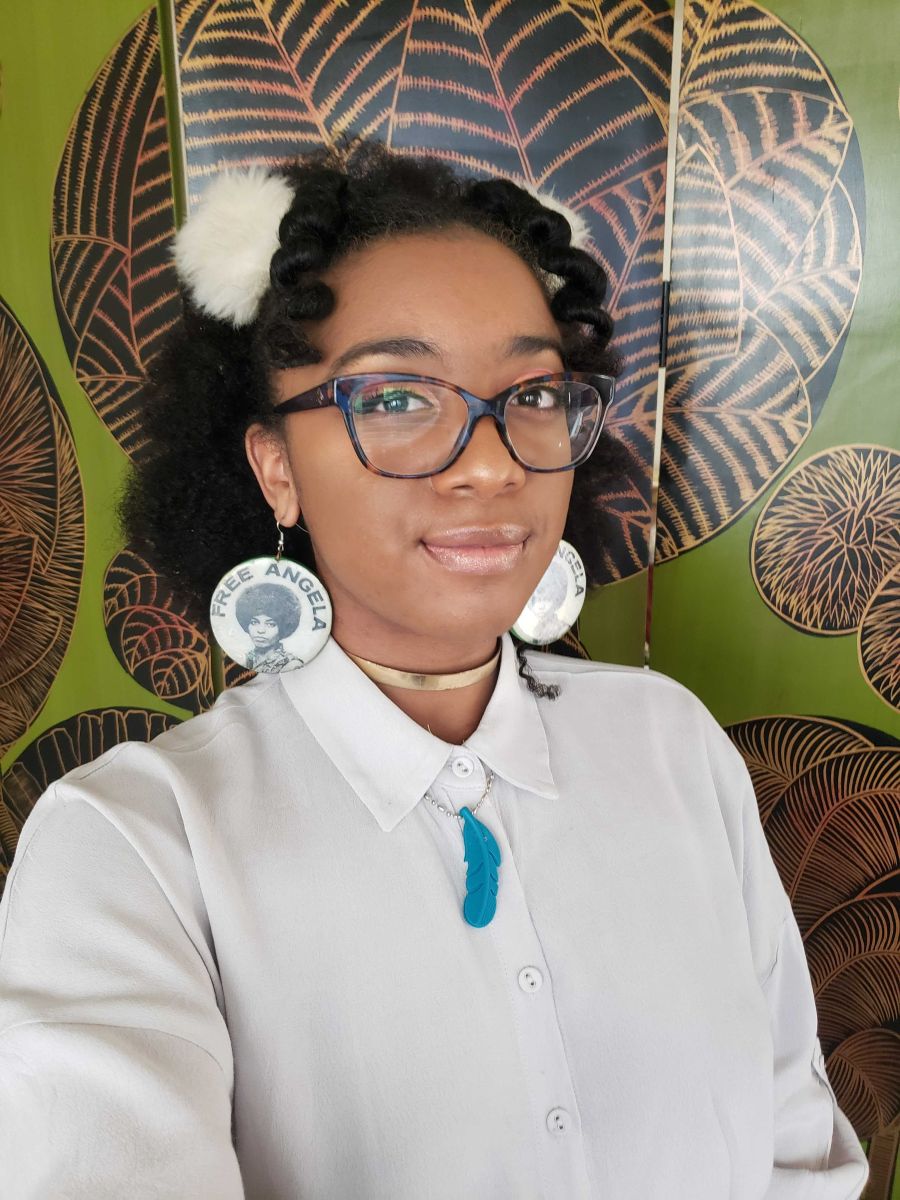 photo of Black NeuroExpansive NeuroQueer person with eyeliner, mascara, curled black hair, cat-eye glasses, 